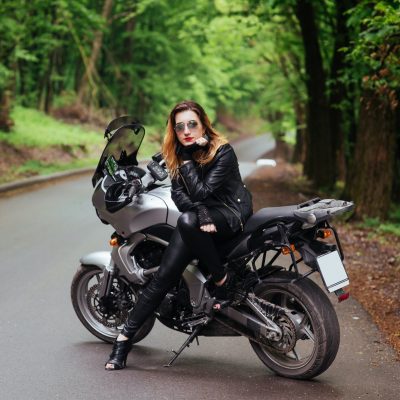 An attractive sexy girl on a sports motorbike posing outside
