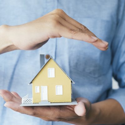 Businessman hand hold the house model saving small house.