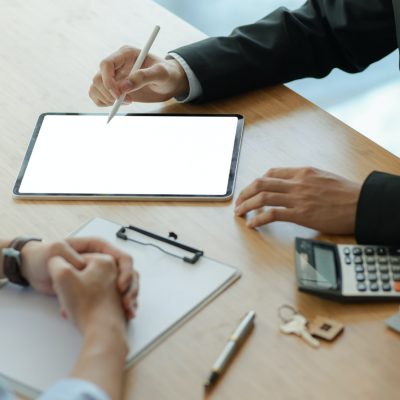 Insurance agents with tablet are introducing real estate insurance programs for customer.