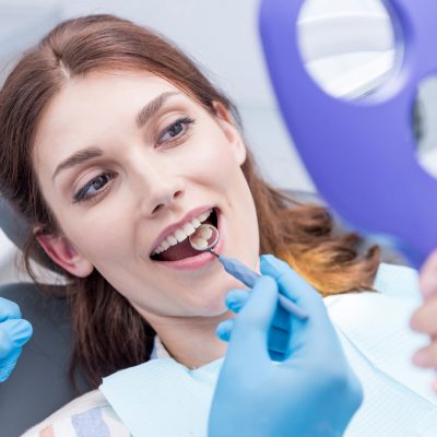 portrait of beautiful woman checking teeth after curing teeth in dental clinic